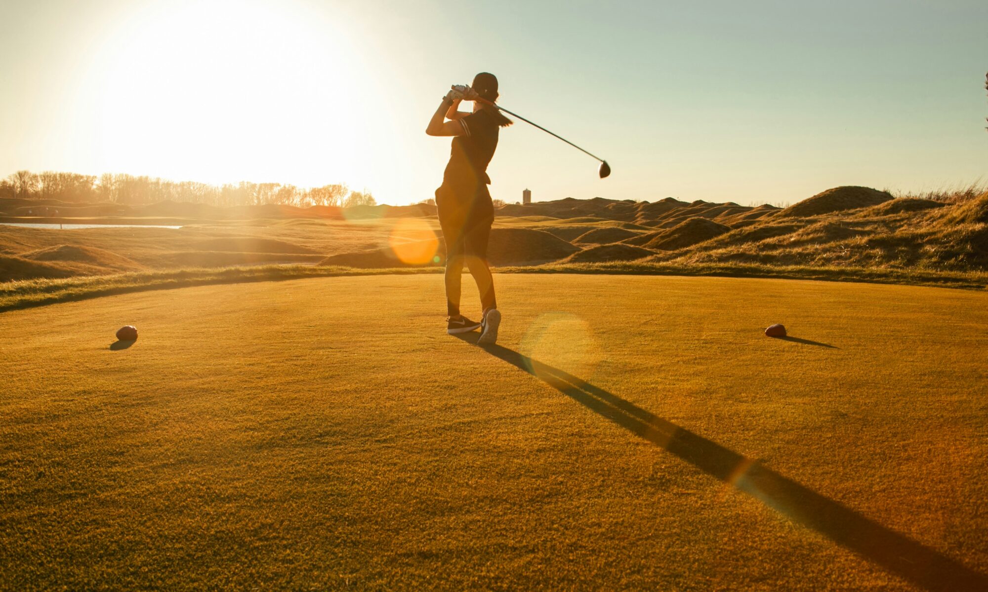 Golferin beim Abschlag auf einem Golfplatz am Morgen